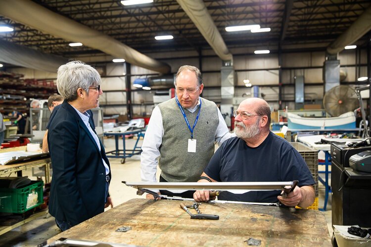 PTM Human Resources Director John Tucker (center) and Ann Austin of Michigan Works (left) chat with employees.