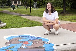 Teagan Georgia poses for a photo beside her mural in downtown St. Clair.