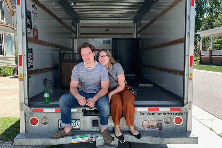 Tyler Moldovan and his girlfriend Alexandra Hand pose for a photo outside of their moving truck after purchasing their first home in Port Huron.