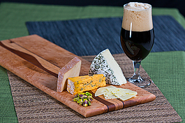 a glass of stout beer and variety cheeses
