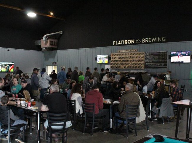 A large crowd gathers in the main hall of Flat Iron Brewing in Manistique.